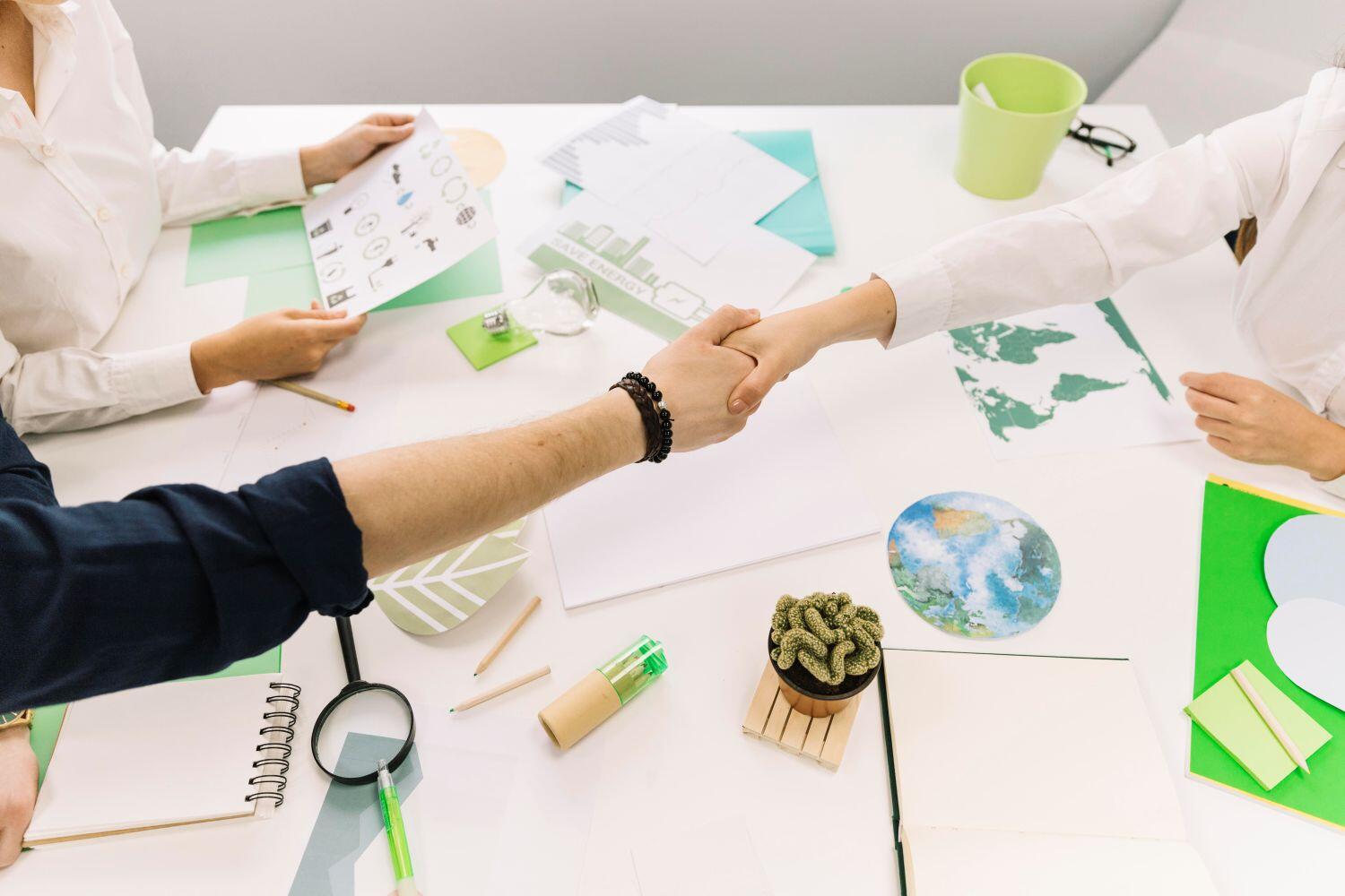 Deux mains se serrent au-dessus d’un bureau